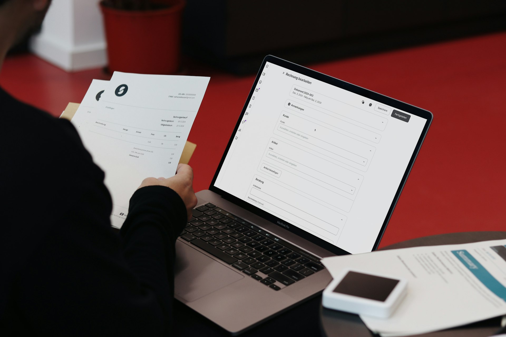 Eine Person prüft Belege und arbeitet dabei am Laptop